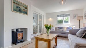 A cozy living room with a fireplace, a sofa, a coffee table, and a painting on the wall.