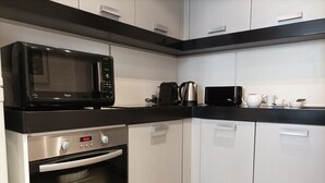 Una cucina con un forno a microonde nero, una macchina da caffè, un bollitore e un tostapane.