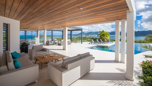 A modern outdoor living area with a pool, white furniture, and a view of the ocean. - La Siesta (4/5 Rooms) (La Baie Nettle)