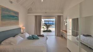 A hotel room with a bed, a ceiling fan, a painting, and a view of the sea. - La Siesta (4/5 Rooms) (La Baie Nettle)