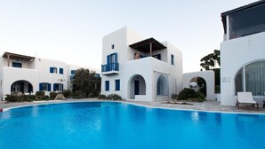 A modern building with a swimming pool, featuring white and blue architectural elements and a balcony. - Glamorous 2BR Villa in Ornos w Sea View (Mykonos)