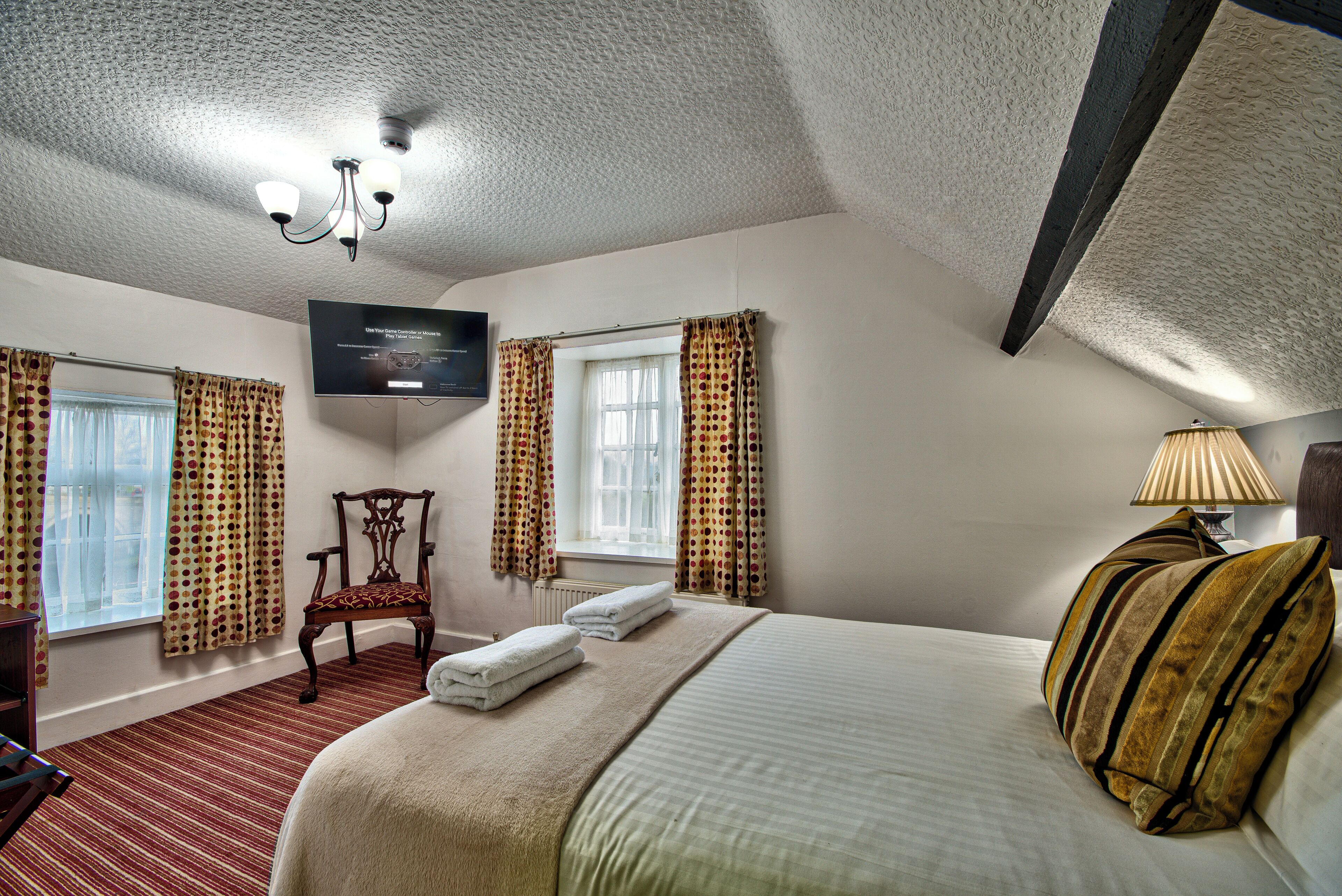 Een hotelkamer met een bed, een stoel, een televisie en gordijnen.
