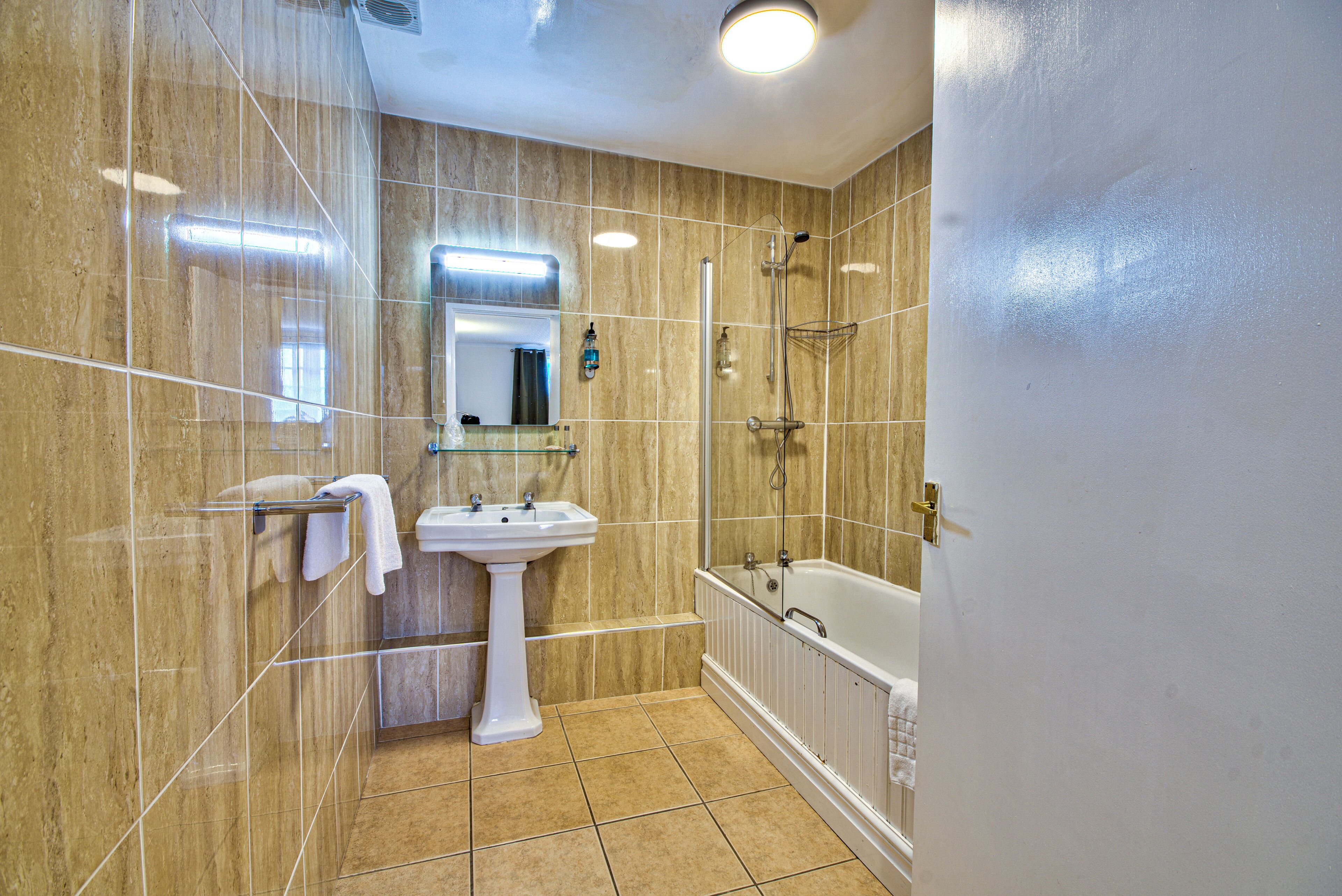A bathroom with a sink, mirror, shower, and bathtub.