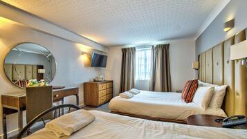 A hotel room with two beds, a desk, a chair, a dresser, a TV, and a window with curtains.