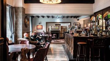 A bar area with wooden furniture, a fireplace, and a bar stocked with bottles.