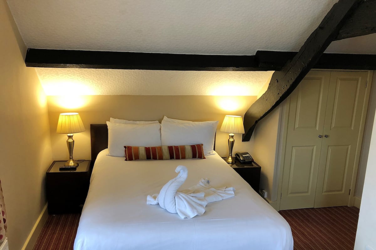 A hotel room with a large bed, two bedside lamps, a telephone, and a door.
