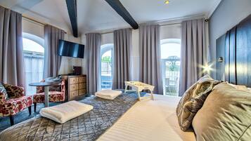 Une chambre d’hôtel équipée d’un lit, d’un bureau, d’une télévision et offrant une vue sur l’extérieur.