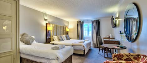 A hotel room with two beds, a desk, a chair, and a large mirror.