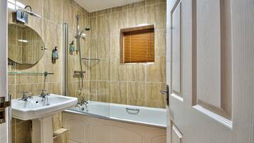 A bathroom with a sink, mirror, bathtub, shower, and window.