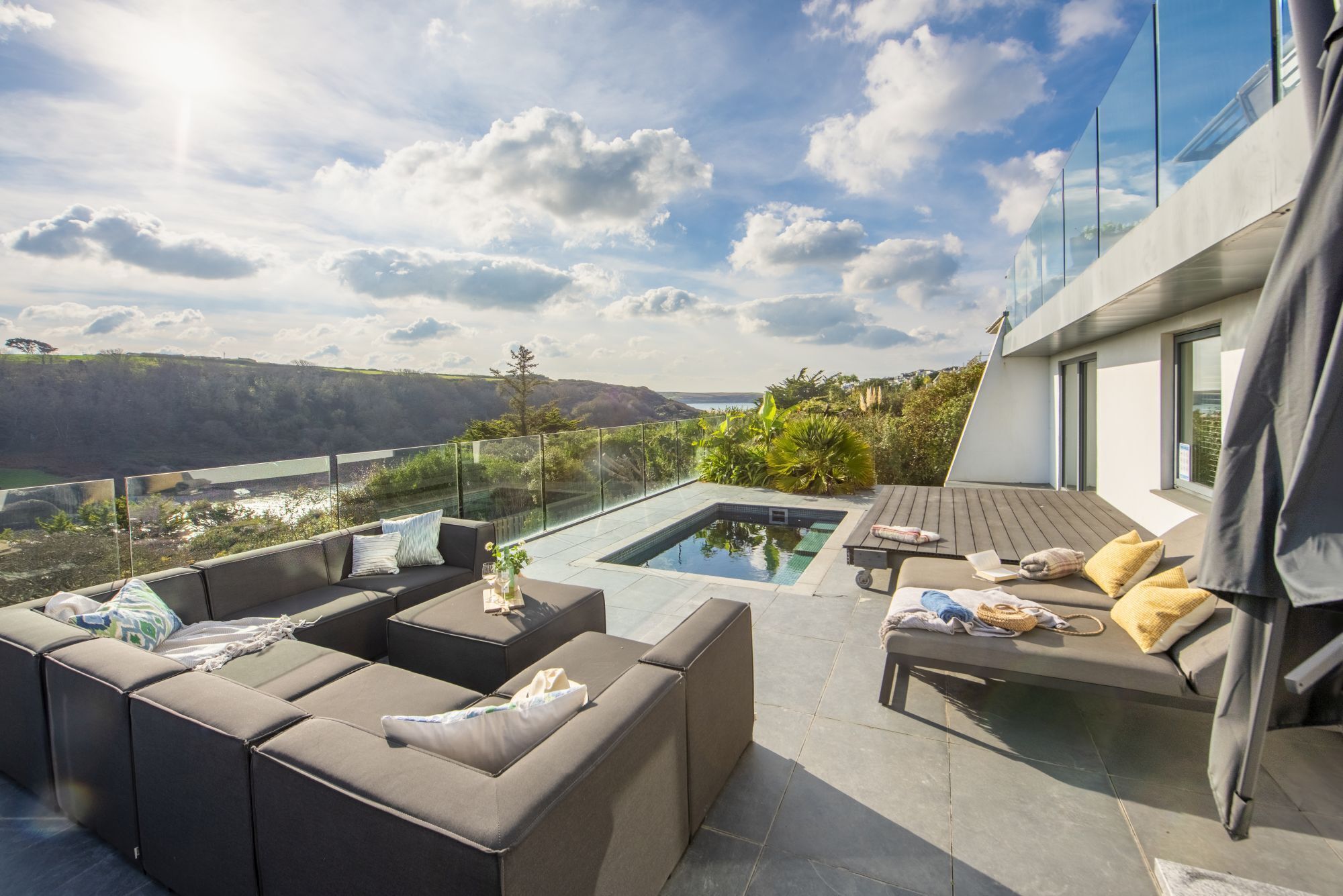 A modern outdoor living area with a pool, seating, and a scenic view.