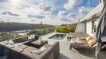 A modern outdoor living area with a pool, seating, and a scenic view.