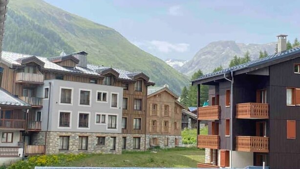 A mountain resort with multi-story buildings featuring balconies and stone facades. - Appartement de Standing 6/7p Avec Parking Couvert (Val-d'Isère)
