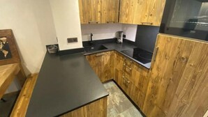 A kitchen with wooden cabinets, a black countertop, and a built-in oven. - Appartement de Standing 6/7p Avec Parking Couvert (Val-d'Isère)