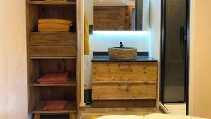 A bathroom with a wooden vanity, a sink with a stone basin, and a glass shower enclosure. - Appartement de Standing 6/7p Avec Parking Couvert (Val-d'Isère)