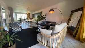 Un salón amplio con sofá, sillones, una mesa de centro y zona de comedor.