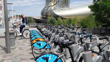 A row of electric bikes with blue and yellow accents parked on a cobblestone path, with a modern building in the background.