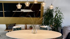 Un comedor moderno con una mesa redonda, sillas blancas e iluminación colgante.