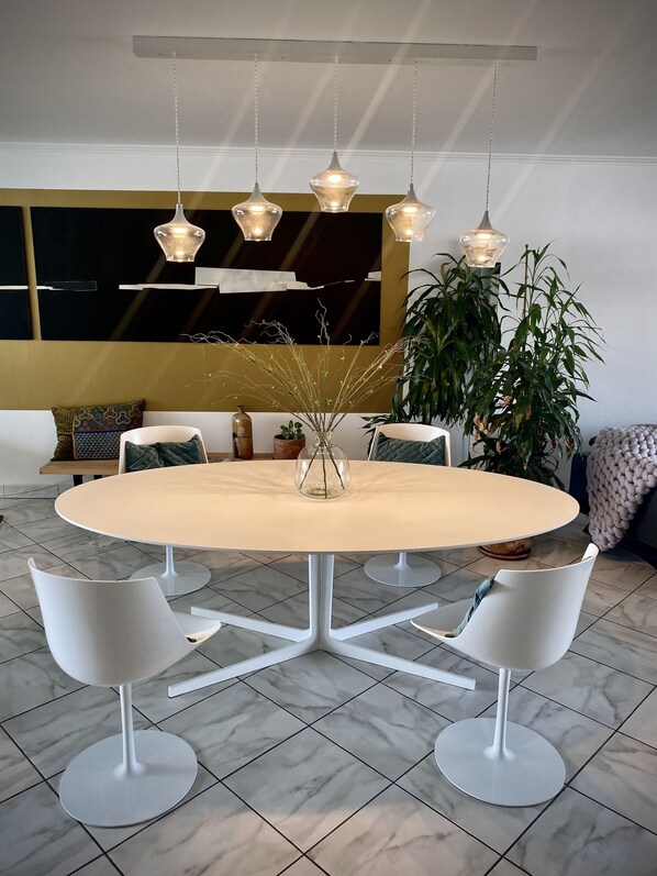 Un comedor moderno con una mesa redonda, sillas blancas e iluminación colgante.