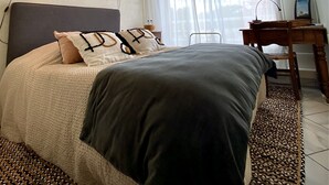 Un dormitorio con cama, lámparas de noche, escritorio y televisor.