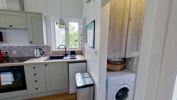 A compact kitchen with a sink, dishwasher, and a washing machine.