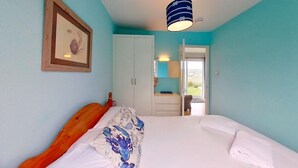 Une chambre à coucher comprenant un lit, une armoire, une porte donnant sur un balcon et un tableau encadré accroché au mur.