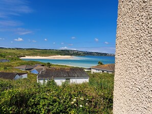 A coastal view with houses, a sandy beach, and a clear blue sky. - B44 Sea Urchin, Riviere Towans (Hayle)