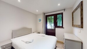 A bedroom with a bed, a nightstand, a dresser, a door, and a window. - 48 Trevithick Court, Tolroy Manor (Hayle)