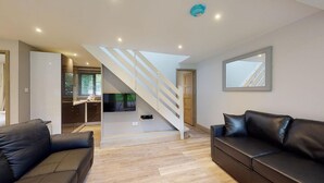 A modern living room with a staircase, leather sofas, and a large window. - 48 Trevithick Court, Tolroy Manor (Hayle)