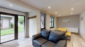 Relax in a spacious living area with a sofa, dining table, and sliding glass door leading to a garden view.