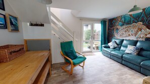 A living room with a wooden bench, a teal armchair, and a blue sofa with patterned cushions. - 45 Strawberry Hill, Tolroy Manor (Hayle)