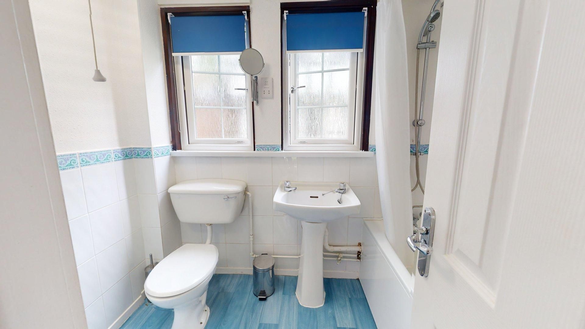 Un baño pequeño con inodoro, lavamanos y ducha.