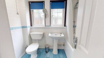 Un baño pequeño con inodoro, lavamanos y ducha.