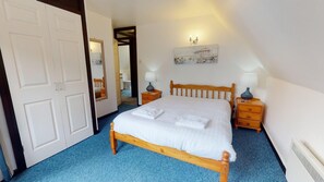 A bedroom with a wooden bed, two bedside tables with lamps, a mirror, and a painting on the wall.