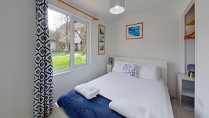 A bedroom with a bed, a window, a bedside table, and a wardrobe. - 25 Trevithick Court, Tolroy Manor (Hayle)