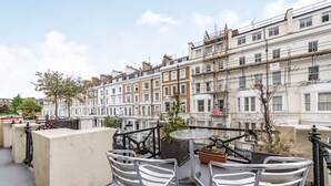 A terrace with metal chairs and a table, overlooking a row of traditional terraced houses.
