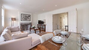 A modern living room with a sofa set, a fireplace, a television, and a dining area with a table set for a meal.