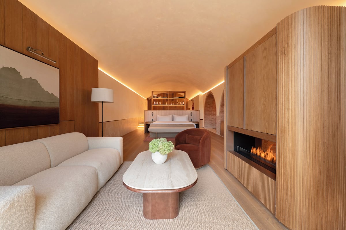 A modern living room with a sofa, a coffee table, a fireplace, and a bookshelf.