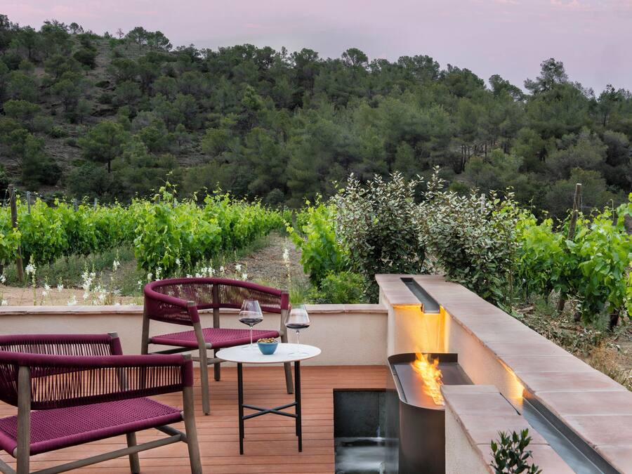 Un espacio de estar al aire libre con sillas de mimbre y una mesa, con vistas a un viñedo.
