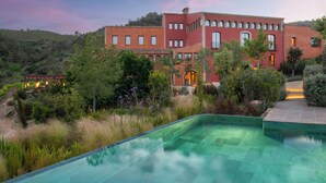 A large, red building with multiple windows and a pool in the foreground. - Gran Hotel Mas d' en Bruno (Torroja del Priorat)