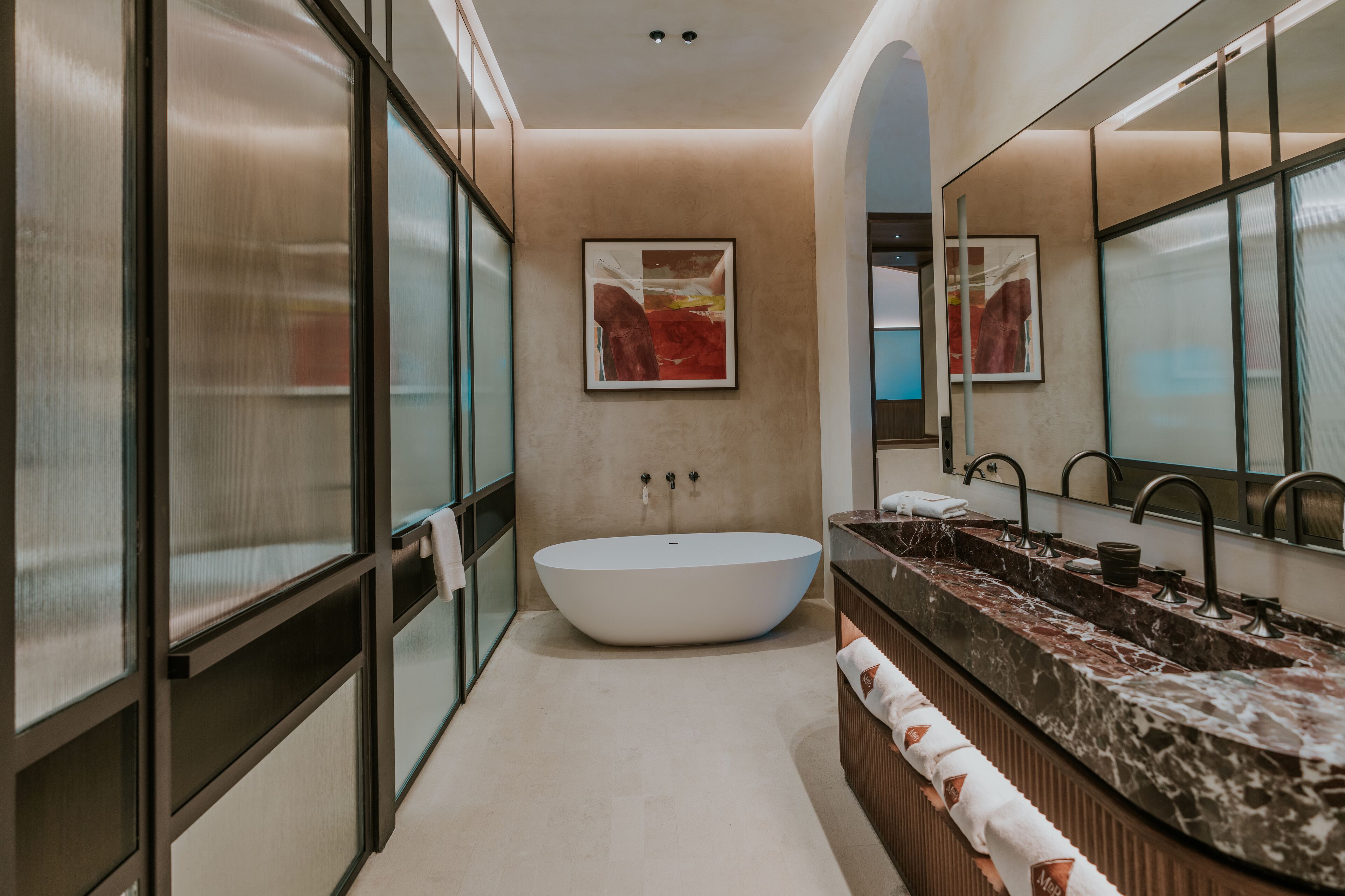 Un baño moderno con una bañera independiente, un espejo grande y una encimera de mármol.