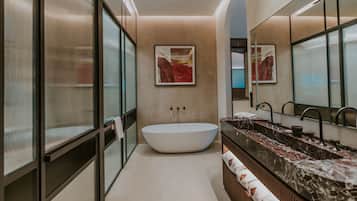 Un baño moderno con una bañera independiente, un espejo grande y una encimera de mármol.
