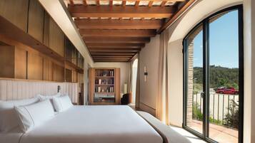 Una habitación de hotel moderna con una cama grande, estanterías empotradas y un balcón con vistas panorámicas.