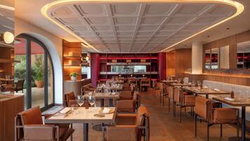 A modern restaurant with a central open dining area, multiple tables, and a view of the outdoors.