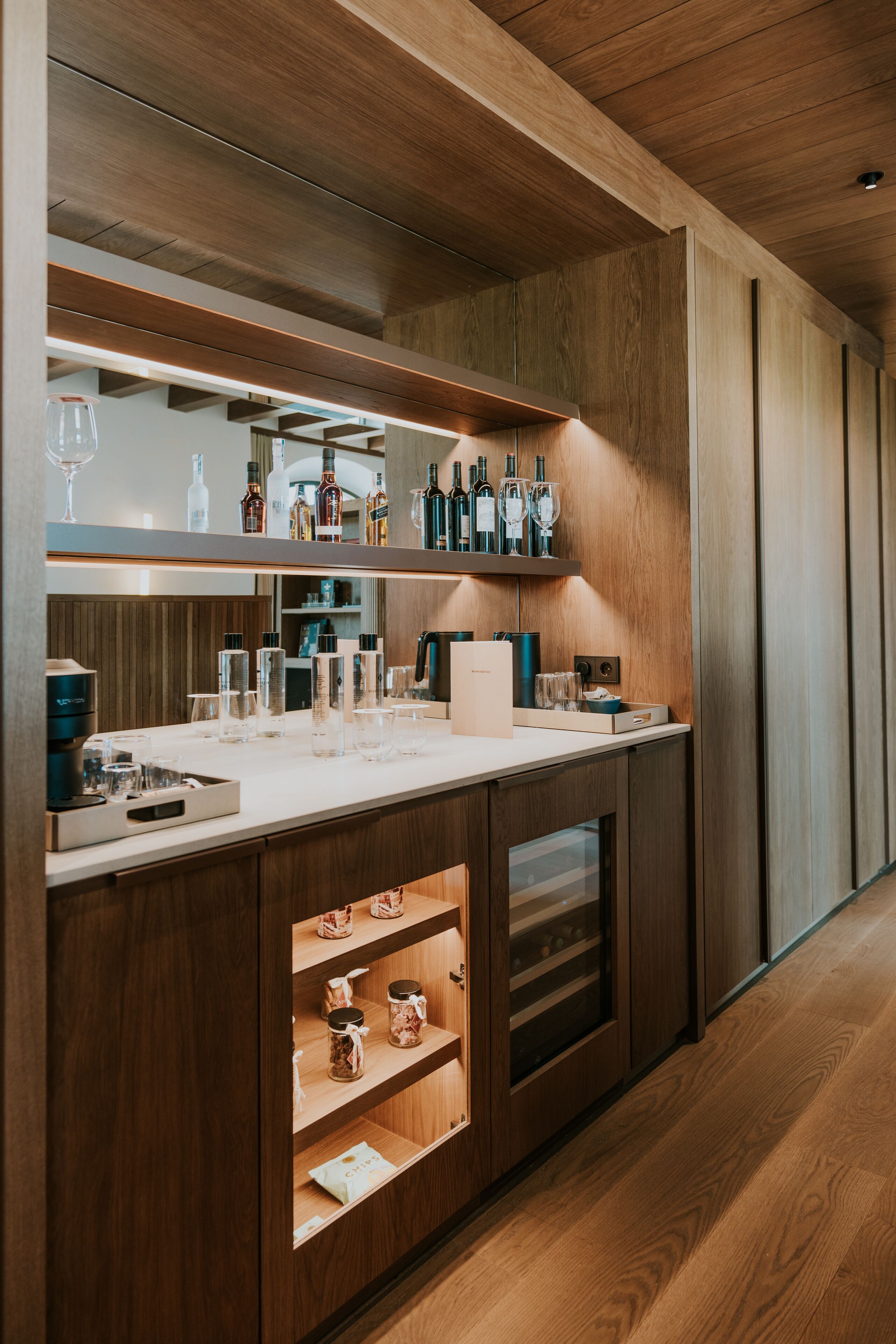 Une cuisine moderne avec des meubles en bois, un plan de travail et un meuble à vin intégré.
