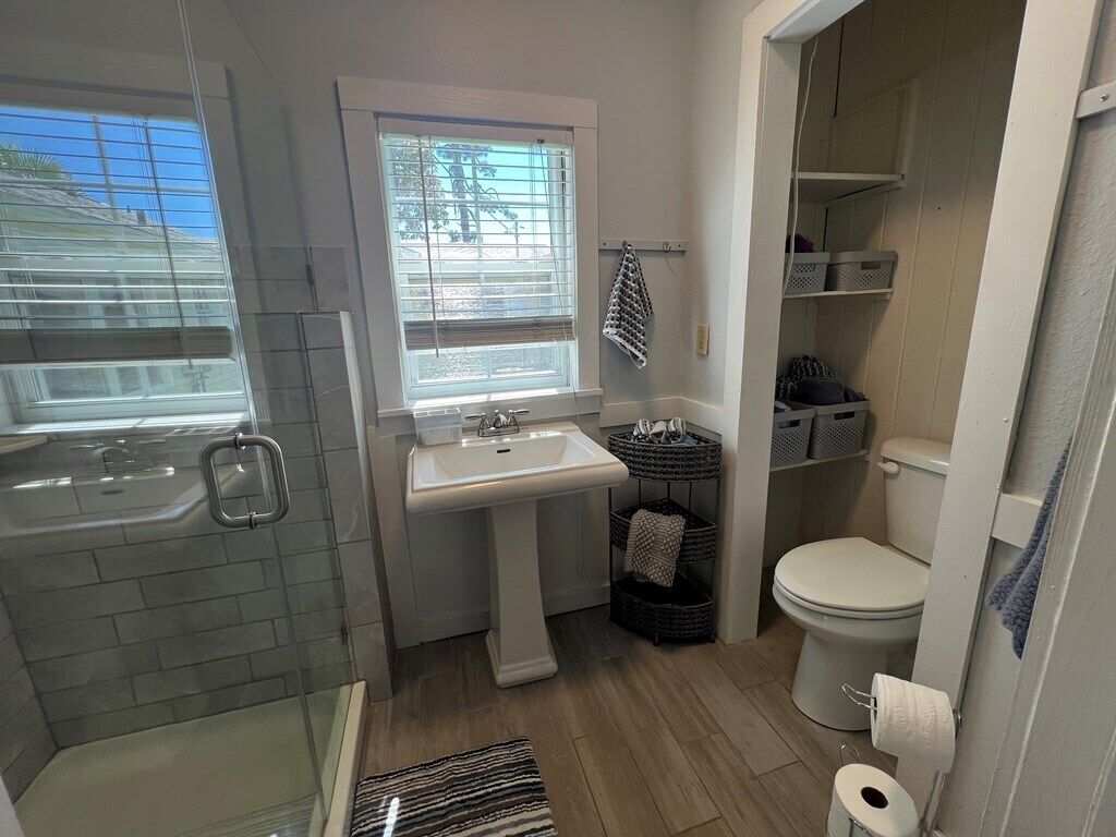 Ein Badezimmer mit Badewanne, Waschbecken und Toilette. Körbe und Regale mit Toilettenartikeln sind vorhanden.