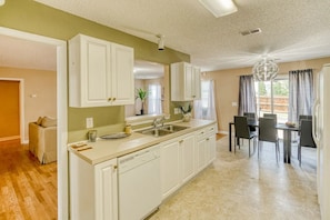 A kitchen with white cabinets, a sink, and a dining area with a table and chairs.