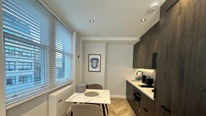 Una cocina compacta con una mesa de comedor, una silla y un ventanal con persianas.