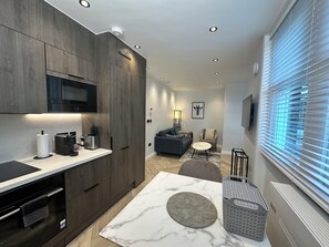Une cuisine moderne avec des meubles de couleur sombre, un four à micro-ondes encastré et un plan de travail en marbre.