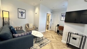 Una sala de estar moderna con sofá, sillón, mesa de centro y televisor de pantalla plana montado en la pared.