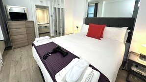 Ett modernt hotellrum med en stor säng, en platt-TV, en byrå och en rymlig klädkammare.